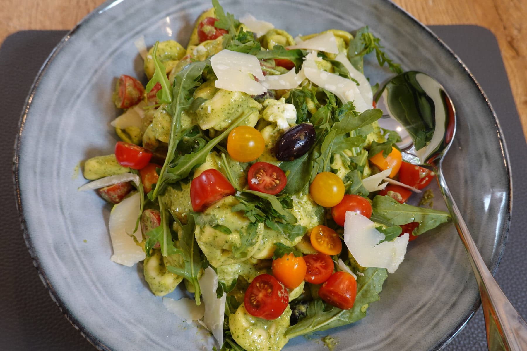 Ensalada tibia de tortellini con pesto de albahaca, mozzarella, tomates y aceitunas