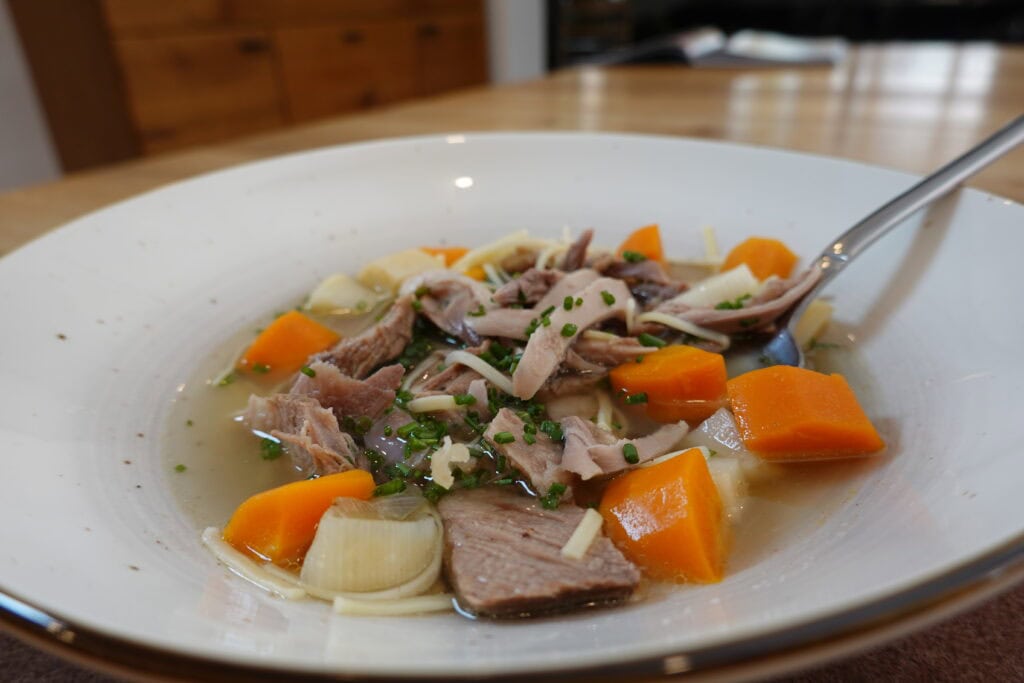 Alt-Wiener Suppentopf mit Rind und Huhn im tiefen Teller, mit Karotten, Lauch, Nudeln und Schnittlauch