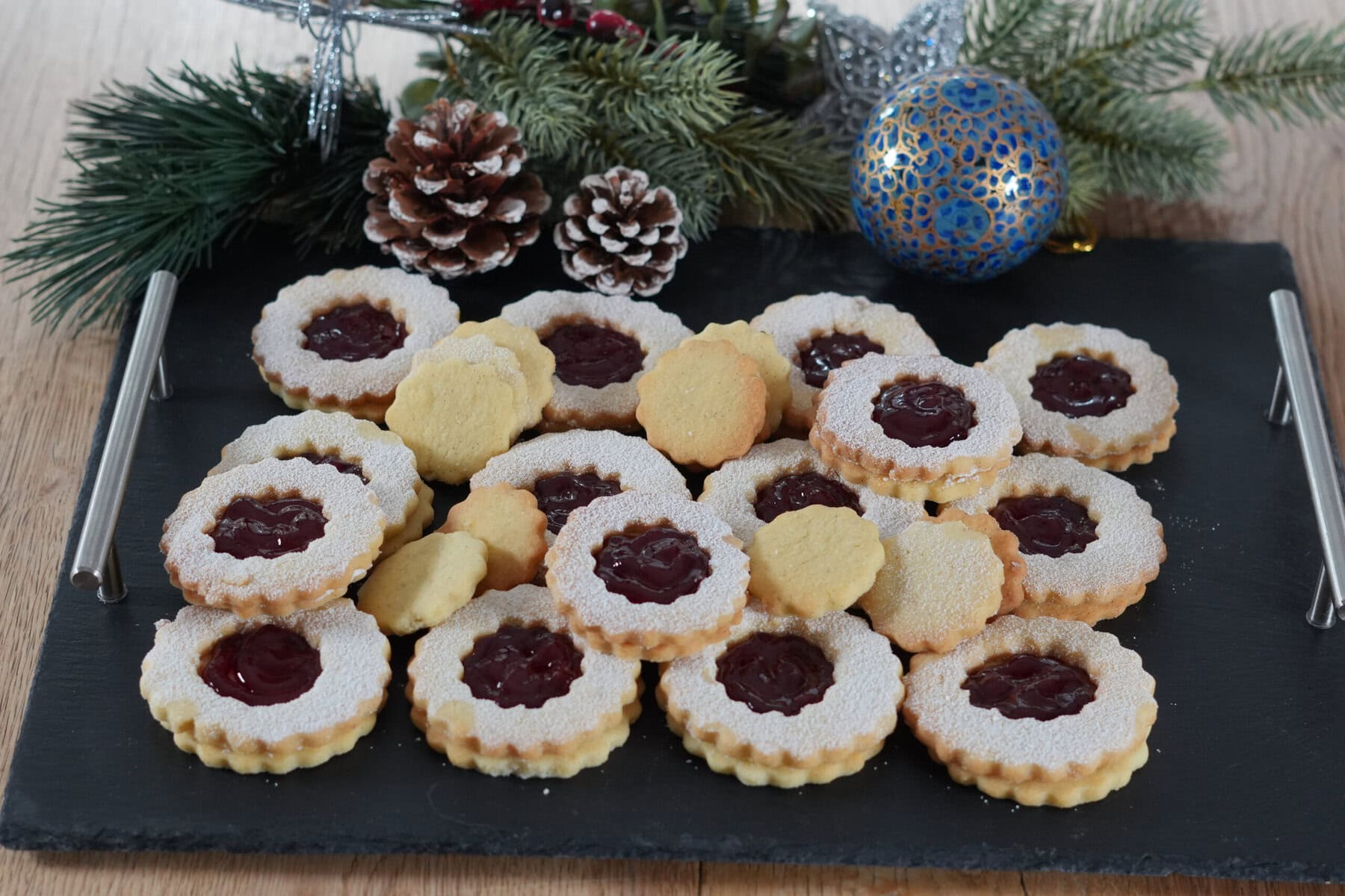 Linzer Augen und Spitzbuben auf einer schwarzen Schiefertafel – frisch gebacken und mit Puderzucker bestäubt
