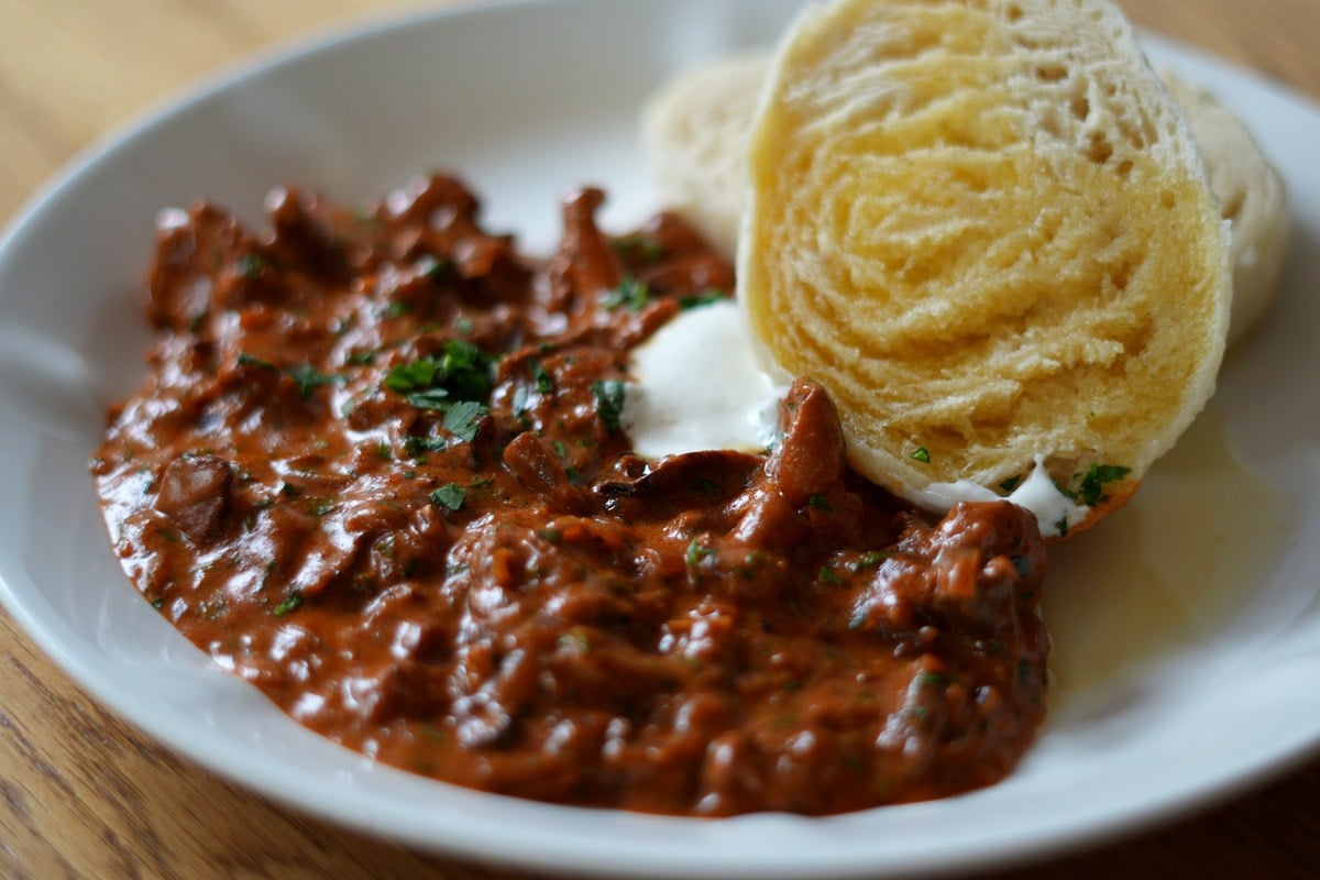 Nahaufnahme von Schwammerlgulasch mit cremiger Paprika-Sauerrahm-Sauce und böhmischem Knödel.