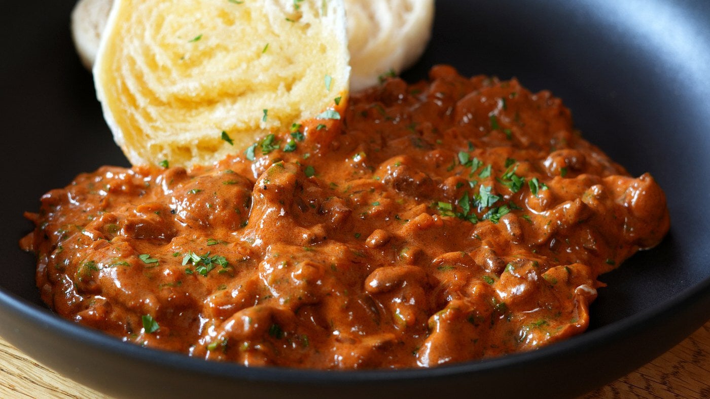 Schwammerlgulasch mit Eierschwammerln und böhmischen Knödeln in einer schwarzen Schale.