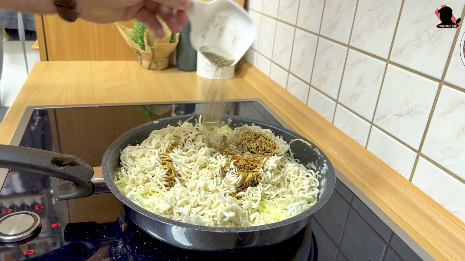 Ketjap Manis wird über Nudeln und Spitzkohl in die Pfanne gegossen